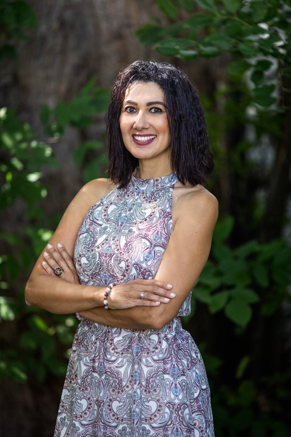 Rania in a patterned dress with arms crossed, photographed for a professional profile